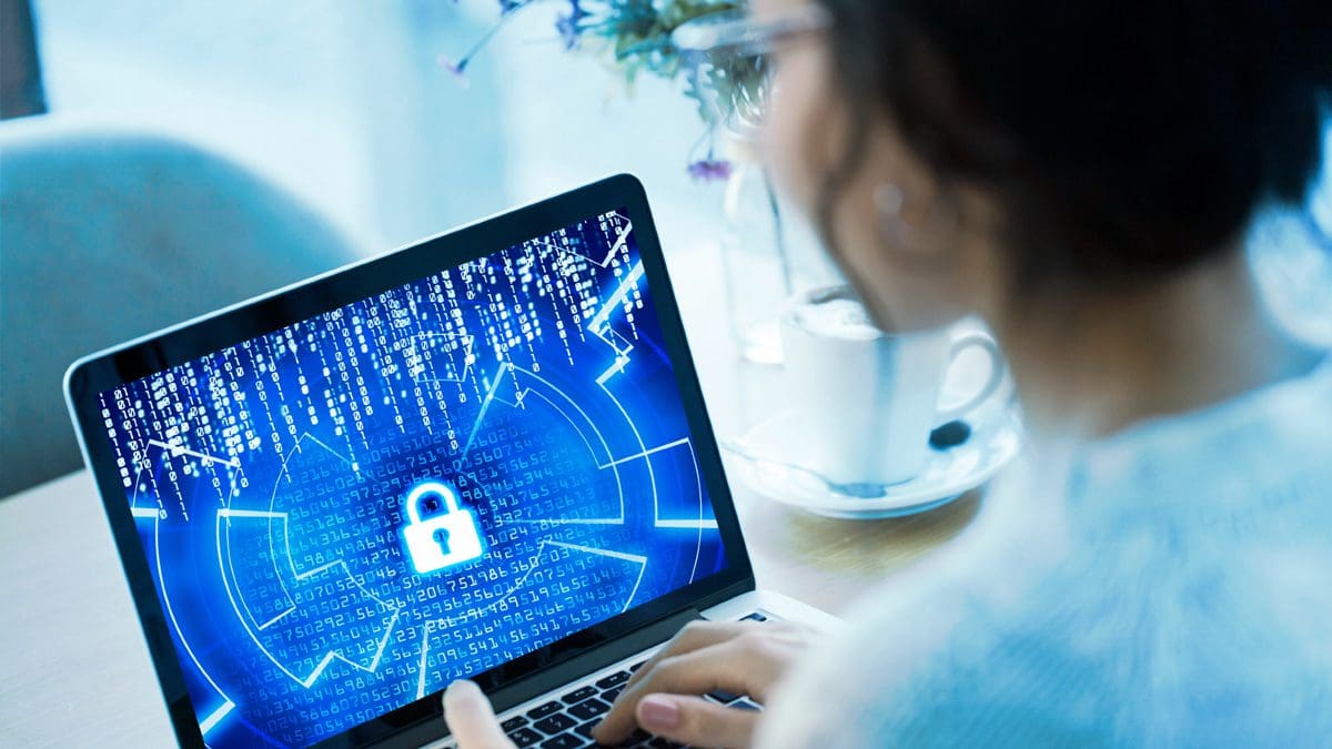Woman using a laptop. The screen shows a lock and cascading code.