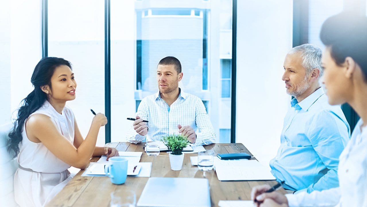 A group of colleagues talking at a conference table.