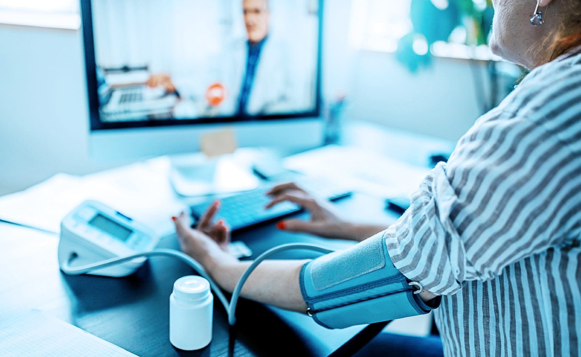 Patient connecting remotely with a doctor while measuring their blood pressure.