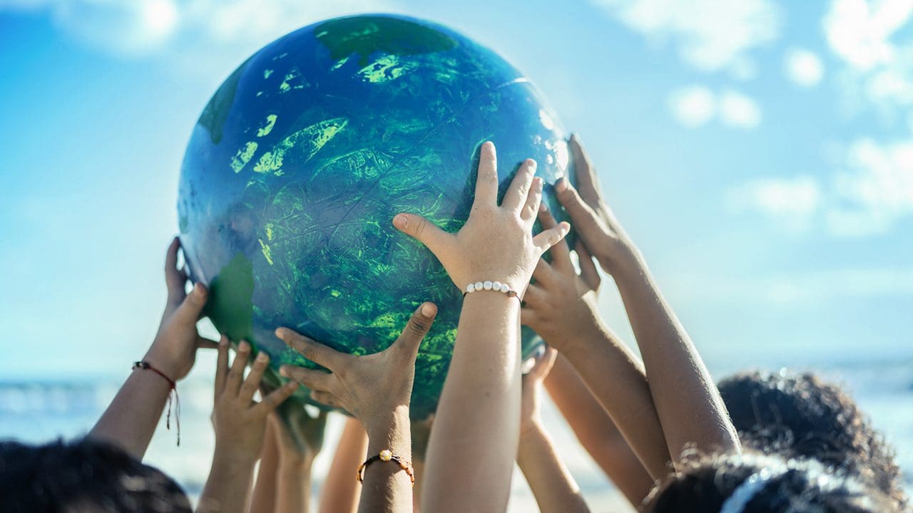 Children's hands on a model of the globe.