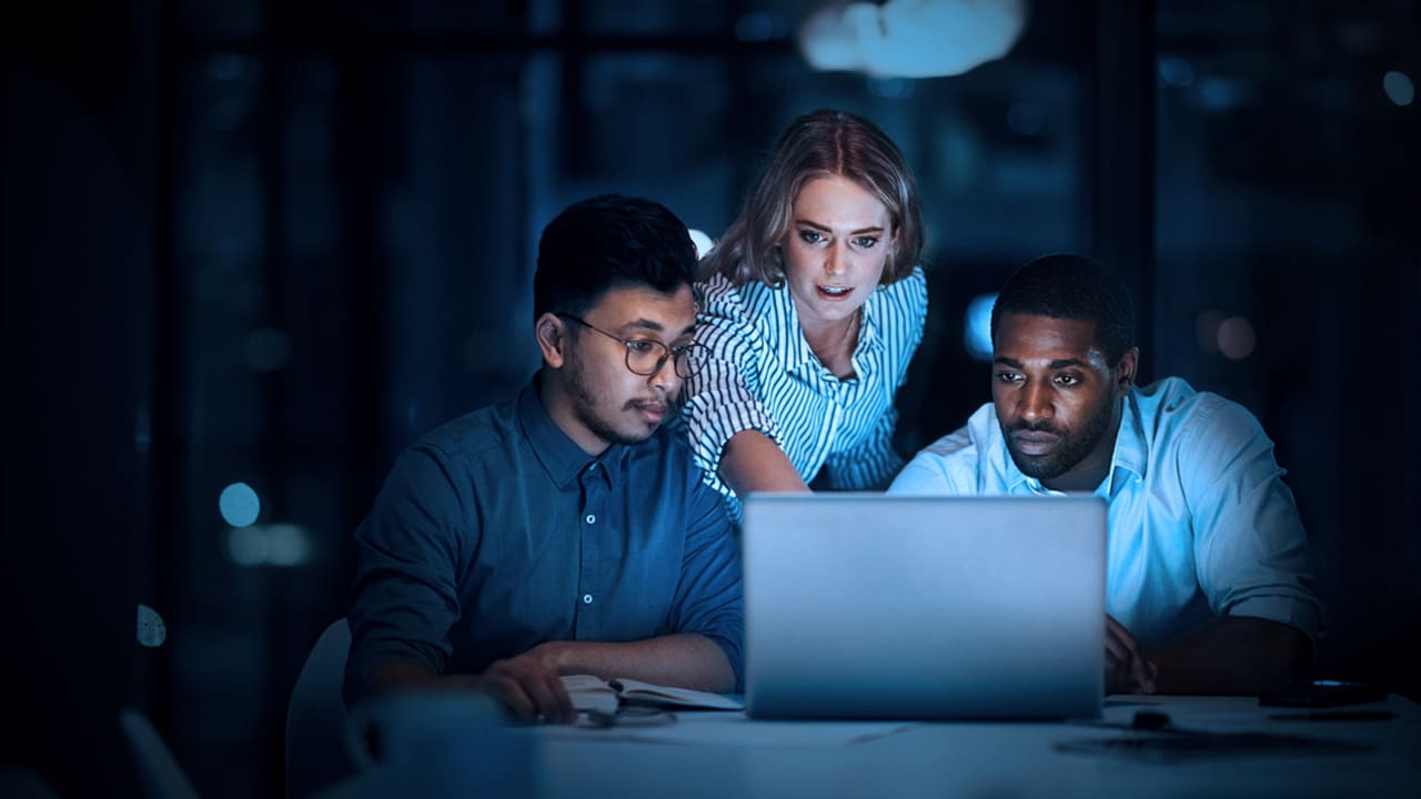 Three people looking at a computer