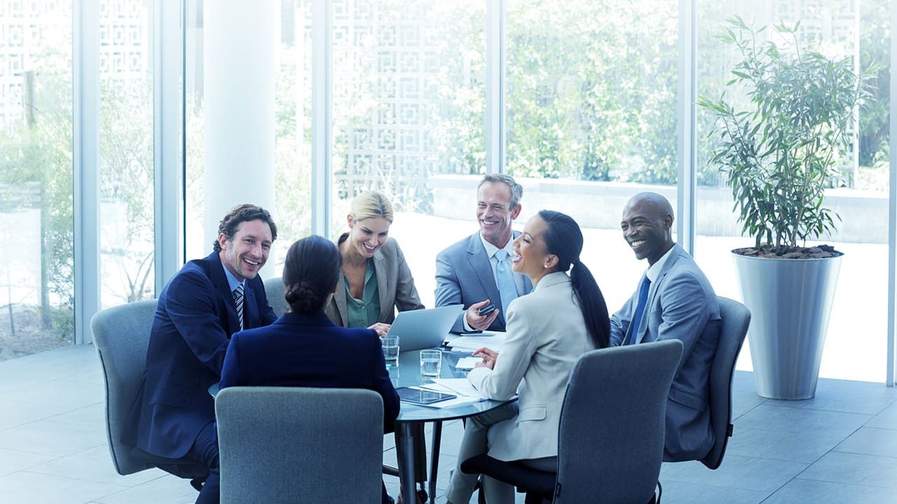 Several people sitting at a table conducting a meeting.